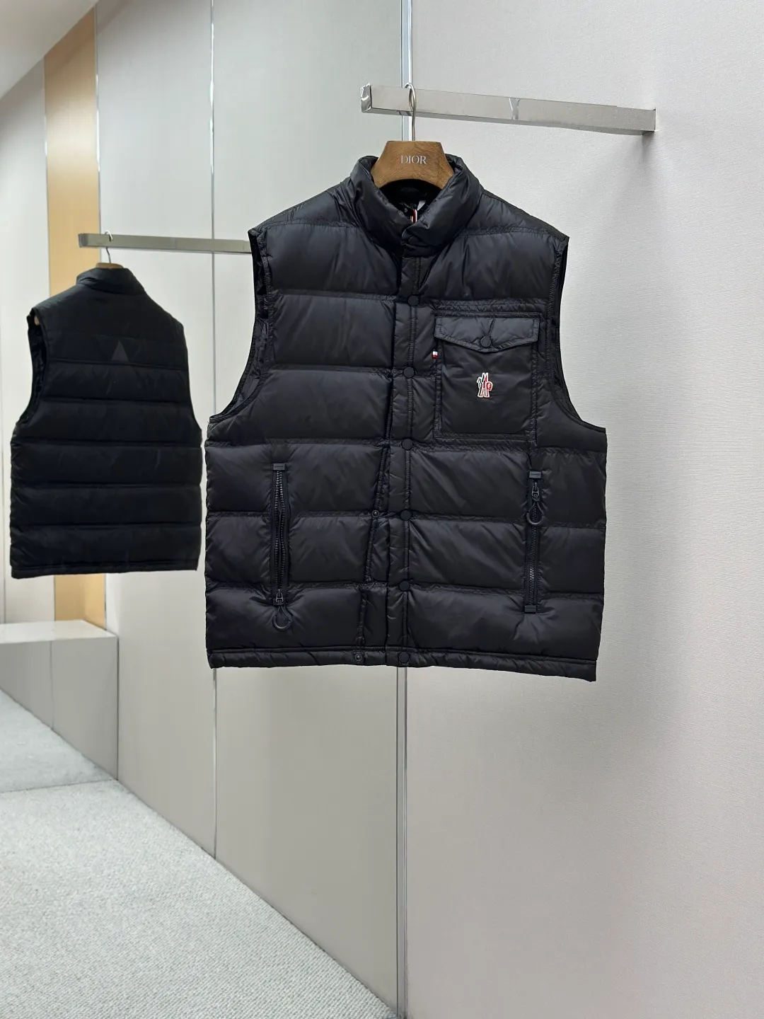 P680 MONCLER down vest with reflective markings Fabric selection: Made of ultra-fine nylon yarn woven in a high-density manner. The number of yarns per unit area is large, and the gaps between the yarns are very small, which can effectively block the penetration of cold wind. The fine weave keeps it lightweight and soft to the touch, physically restricting the lightweight down fibers from slipping through the gaps. Nylon fiber itself has good wear resistance and is not easy to snag, which significantly extends its service life and can easily cope with the needs of multiple scenarios.  Lining selection: The lining is made of 100% polyester fiber high-density weaving. The thickness of 0.08mm avoids increasing the overall weight and makes it smooth to wear. The high-density weaving structure forms a wind resistance layer to protect the thermal efficiency of the thermal insulation layer from loss. At the same time, it can withstand the expansion pressure of down and prevent deformation and damage after long-term use.  High-quality filling: 90 white duck down is selected, with a weight of 130g, ensuring excellent thermal insulation performance. After strict screening and processing, the velvet is not easy to get drilled, ensuring durability.  Process: Through the reflective cloth punching process, the logo is regularly arranged on the triangular reflective mark with dozens of small holes, which not only improves the functionality, but also strengthens the recognition and aesthetics.   Accessories: Customized snap buttons, customized zipper pullers, customized badges, customized elastic buckles, etc. SIZE: 1 2 3 4