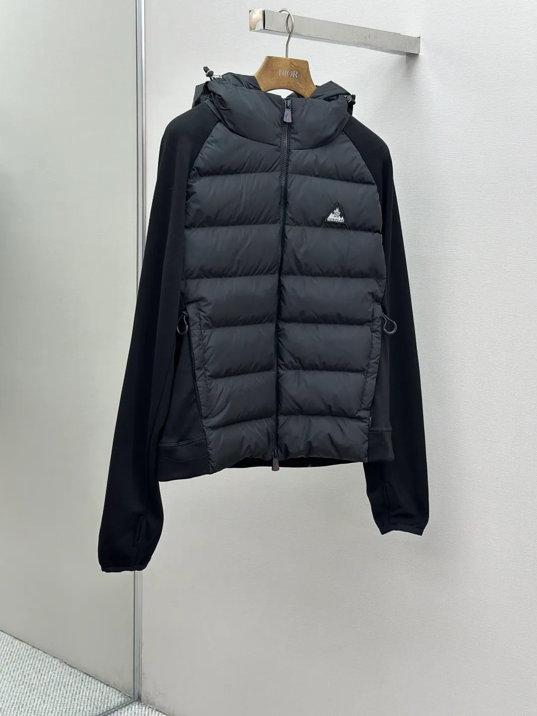 P810 Moncler logo woven splicing down jacket, customized matte crystal lattice air shield velvet and 300D high-density calendered coating, using the new national standard 90 white duck down (welcome to test), full of down, full of warmth, light and fluffy, with the dark green of the overlapping mountains as the background color, all things accumulating, creating its own scenery in silence The Monlcer triangle logo is embellished on the chest, the power aesthetics of the minimalist logo The concentrated down filling in the front area creates dynamic insulation for the core heat dissipation zone of the human body. The hooded down is a moving warm flow barrier for the head and neck, forming a thermal energy circulation system with the front area. The elastic woven sleeves provide freedom of movement with a sense of compression, forming a relaxed and warm philosophy. The real high-end is to let function become the footnote of style. Process 1: Computer mechanical down filling. Prioritize the liner pattern by making a pattern to determine the down filling area and determine the weight of down per square meter according to the original three-dimensional effect. Thus, the amount of down filling for each cut piece is calculated. The computer down filling machine uses a digital weighing unit to achieve stable measurement. Process 2: 3D three-dimensional quilting technology. With the programming system of the CNC quilting machine, the down in different areas is accurately separated to ensure that the filling is evenly fixed after sewing and avoid agglomeration or displacement. Process 3: Computer template machine line running process. The computer template machine line line process shows extremely high neatness and smoothness. The craftsman's precise control of the size during the operation ensures that each line meets the design requirements. The lines of the entire template are smooth and unified, neat and beautiful. Process 4: Triple locking five-thread dense stitching process. Main seam locking + diagonal reinforcement + raw edge wrapping. Triple structure. Forming a three-dimensional protective net at the edge of the fabric to avoid stitch breakage. Paving materials: Customized Moncler zippers. Customized Moncler rope loops. Customized Moncler logo. Customized Moncler eyelets. Customized Moncler trademark. Size: S M L XL