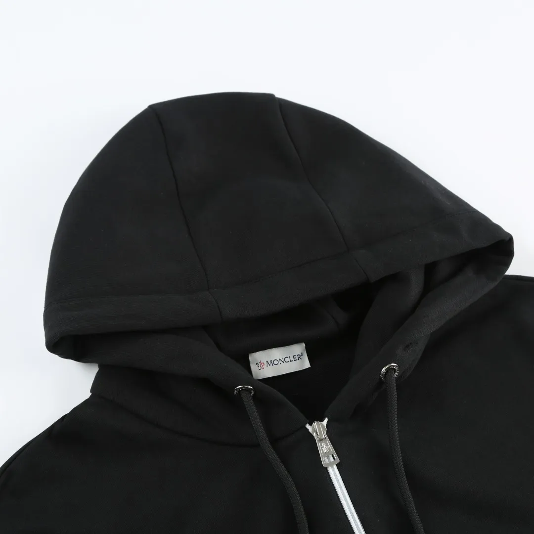 P480 MONCLER printed logo hooded sweatshirt Fabric selection: Made of lightweight turned-over velvet cotton fabric. High-density cotton fiber is used to achieve internal and external differentiation in a single layer of fabric. The outer plain weave is tight and wear-resistant, and the inner layer is formed into a short dense suede surface through a sanding process. The dense plain weave structure resists wind and splashes, the brushed suede surface is skin-friendly, and the short pile has been treated to eliminate static electricity to avoid sticking to the skin. A very small amount of grooved polyester moisture-conducting yarn is embedded in the cotton fiber, which quickly directs sweat from the inner suede surface to the outer layer for evaporation through the capillary effect, solving the problem that the inside-out suede is prone to stuffiness. Process 1: By actively intervening in the shrinkage potential of the cotton fiber, the fabric is achieved from being variable to stable, improving dimensional stability, and at the same time not prone to deformation and wrinkles.  Process 2: Use glue printing to present a high saturation pattern on the center of the cap. Apply even pressure with the scraper and print in 5 steps to ensure full penetration and coverage of the glue. After curing at high temperature, the pigment is firmly combined with the cotton fiber. The ink absorption and penetration characteristics of the cotton fiber make the pattern less likely to fall off due to friction. Accessories: One-to-one customized drawstring head, one-to-one customized zipper puller, one-to-one customized collar label, one-to-one customized badge SIZE: S M L XL
