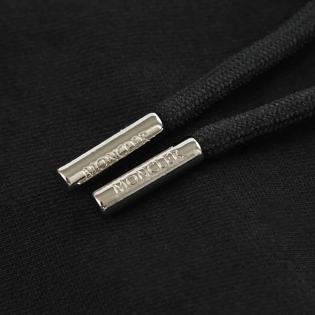 P480 MONCLER printed logo hooded sweatshirt Fabric selection: Made of lightweight turned-over velvet cotton fabric. High-density cotton fiber is used to achieve internal and external differentiation in a single layer of fabric. The outer plain weave is tight and wear-resistant, and the inner layer is formed into a short dense suede surface through a sanding process. The dense plain weave structure resists wind and splashes, the brushed suede surface is skin-friendly, and the short pile has been treated to eliminate static electricity to avoid sticking to the skin. A very small amount of grooved polyester moisture-conducting yarn is embedded in the cotton fiber, which quickly directs sweat from the inner suede surface to the outer layer for evaporation through the capillary effect, solving the problem that the inside-out suede is prone to stuffiness. Process 1: By actively intervening in the shrinkage potential of the cotton fiber, the fabric is achieved from being variable to stable, improving dimensional stability, and at the same time not prone to deformation and wrinkles.  Process 2: Use glue printing to present a high saturation pattern on the center of the cap. Apply even pressure with the scraper and print in 5 steps to ensure full penetration and coverage of the glue. After curing at high temperature, the pigment is firmly combined with the cotton fiber. The ink absorption and penetration characteristics of the cotton fiber make the pattern less likely to fall off due to friction. Accessories: One-to-one customized drawstring head, one-to-one customized zipper puller, one-to-one customized collar label, one-to-one customized badge SIZE: S M L XL