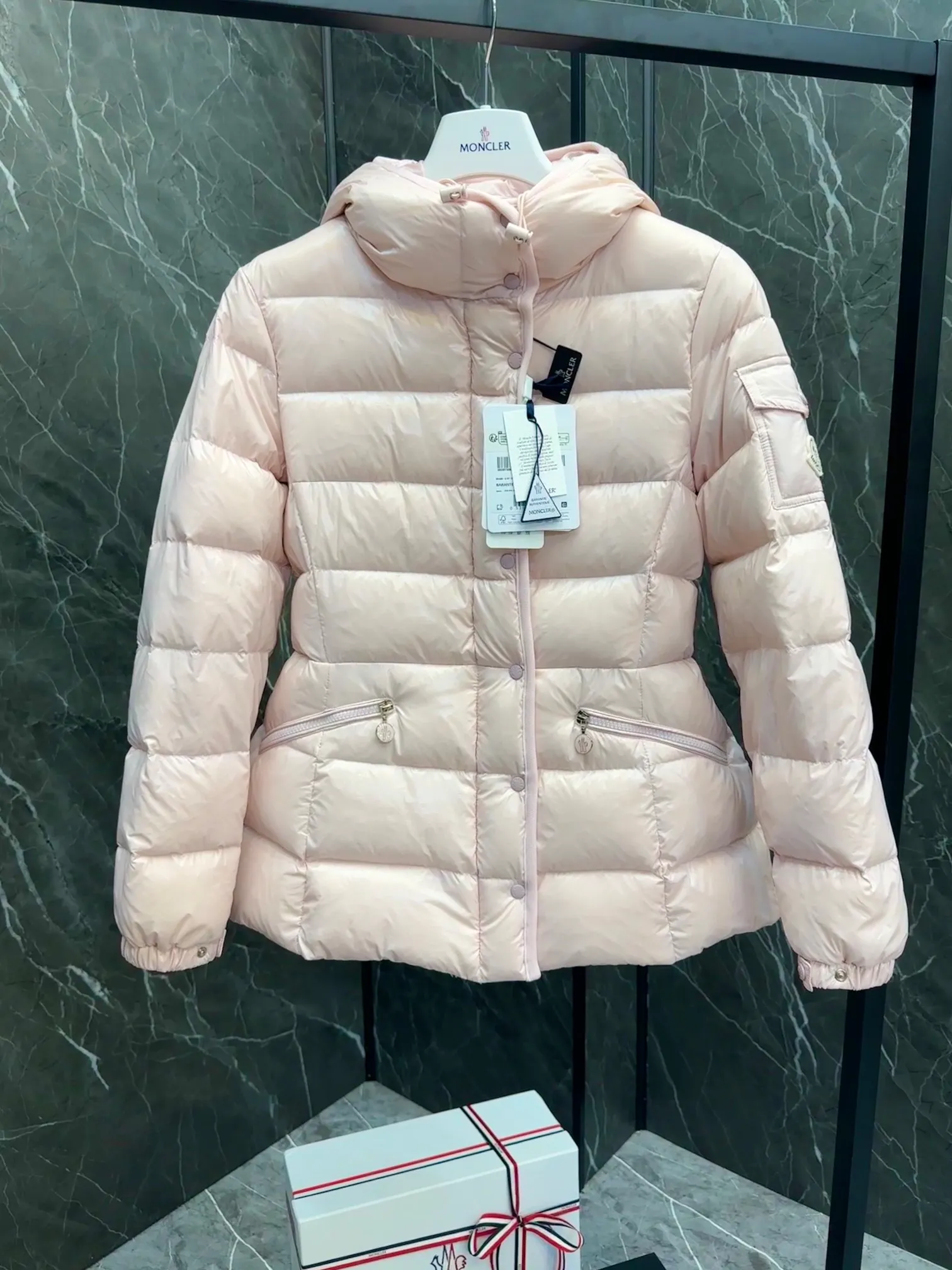 P780 Hot Sale ⬆️Moncler Barante Women’s Short Down Jacket The Barante short down jacket combines femininity with practical functions, reinterpreting the aesthetic style of the 1970s for modern women. The Barante down jacket is made from lustrous nylon and is inspired by the 1970s. It adopts a waist design and presents an A-line silhouette, highlighting a feminine style. An adjustable hood and signature logo patch add finishing touches. Details •Made of nylon laqué fabric •Nylon laqué lining •Down filling •Adjustable hood •Zip and snap closure •Suit pocket •Adjustable cuffs Size : 0-3. Snow White/Light Pink/Black.