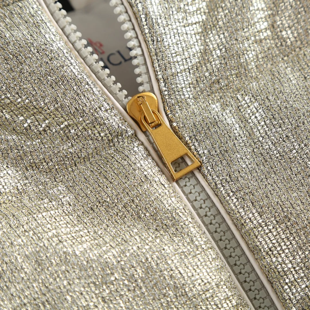 P900 MONCLER gold silk down jacket Fabric selection: Made of 90% 20D ultra-fine nylon and 10% vacuum gold-plated polyester silk. The gold-plated wire is embedded in the nylon base fabric at an oblique angle of 32°. It produces a gradient iridescent effect when illuminated by light, which is comparable to the phantom color gradient of peacock feathers. It forms a visible light spot of 200 meters under the illumination of car lights at night, improving outdoor safety. The high-density woven nylon supports a strong frame with 220 yarns per inch, which effectively locks the down in the physical structure.  Lining selection: High-density lining fabric made of ultra-fine denier, 0.08mm thickness to avoid increasing the overall weight and making it smooth to wear. The high-density woven structure forms a wind resistance layer to protect the thermal efficiency of the thermal layer from loss. It can also withstand the expansion pressure of down and prevent deformation and damage after long-term use.  High-quality filling: 90 white duck down is selected, with a weight of 180g, ensuring excellent thermal insulation performance. After strict screening and processing, the velvet is not easy to get drilled, ensuring durability.  Process: Use anti-velvet silk thread through imported No. 7 needles to reach 13 stitches/inch chain stitch, forming a tight and straight line spacing without skipping stitches. Accessories: One-to-one customized zipper puller, one-to-one customized collar label, one-to-one customized logo SIZE: S M L