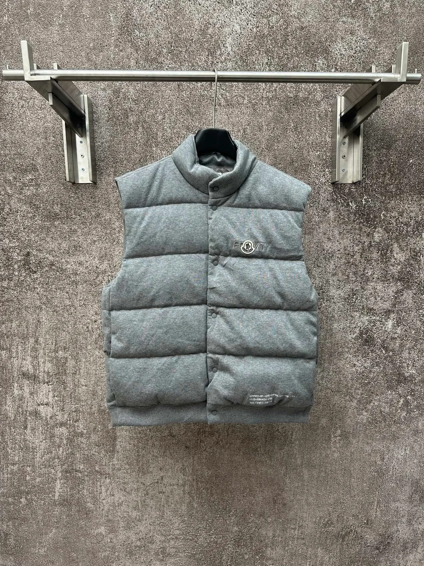 P760 MONCLER cotton embroidered down vest Fabric selection: Lightweight knitted fabric made of 100% cotton fiber. The fiber characteristics are soft to the touch. The knitted structure gives the fabric a certain degree of elasticity in the horizontal and vertical directions. Even though it is a down vest, it can move freely without any sense of restraint. The air circulates freely between the coils and has good breathability. It is not easy to accumulate moisture inside, improving the wearing experience. Lining fabric: The high-density lining is woven with ultra-fine nylon denier, with a thickness of 0.08mm to avoid increasing the overall weight and making it smooth to wear. The high-density woven structure forms a wind resistance layer to protect the thermal efficiency of the thermal layer from loss. It can also withstand the expansion pressure of down and prevent deformation and damage after long-term use.  Process: The high-precision computing system of the computerized embroidery machine controls the coordinated operation of the machine head, needle bar, and bobbin. The fabric frame moves accurately in the horizontal and vertical directions to form a stitch track. The upper and lower thread tensions are adjusted to ensure that the stitches are smooth and free of floating threads. The chest, lower front and lower back panels are decorated with three different letter embroideries. The finished product has clear patterns and no burrs on the edges.  90 national standard high-quality white duck down: Selected high-fill down, with a fill power of 650fp, light and warm, with excellent temperature locking performance and good resilience.  Accessories: One-to-one customized badges, One-to-one customized snaps, One-to-one customized three-label, One-to-one customized zipper pullers SIZE: S M L XL
