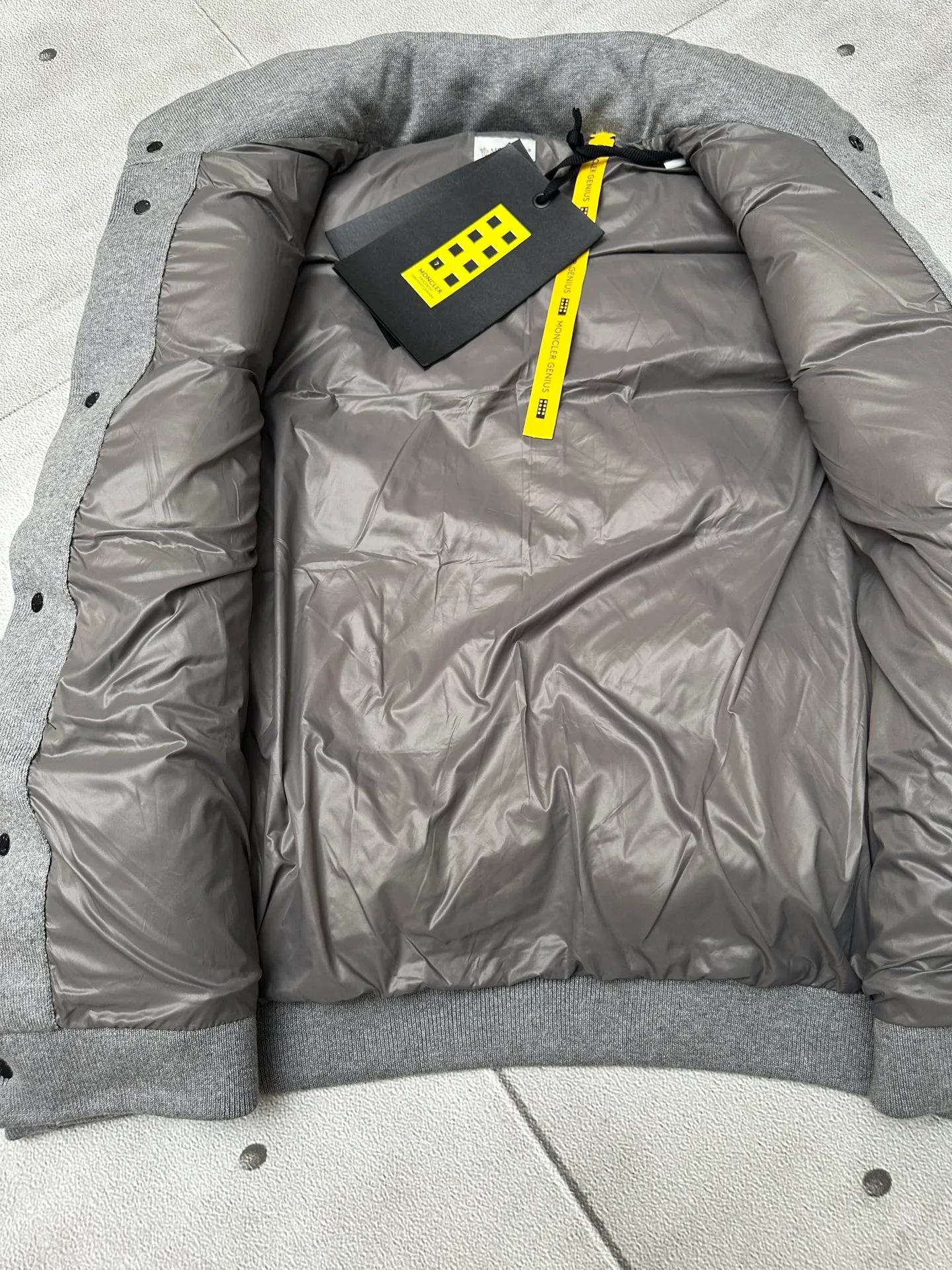 P760 MONCLER cotton embroidered down vest Fabric selection: Lightweight knitted fabric made of 100% cotton fiber. The fiber characteristics are soft to the touch. The knitted structure gives the fabric a certain degree of elasticity in the horizontal and vertical directions. Even though it is a down vest, it can move freely without any sense of restraint. The air circulates freely between the coils and has good breathability. It is not easy to accumulate moisture inside, improving the wearing experience. Lining fabric: The high-density lining is woven with ultra-fine nylon denier, with a thickness of 0.08mm to avoid increasing the overall weight and making it smooth to wear. The high-density woven structure forms a wind resistance layer to protect the thermal efficiency of the thermal layer from loss. It can also withstand the expansion pressure of down and prevent deformation and damage after long-term use.  Process: The high-precision computing system of the computerized embroidery machine controls the coordinated operation of the machine head, needle bar, and bobbin. The fabric frame moves accurately in the horizontal and vertical directions to form a stitch track. The upper and lower thread tensions are adjusted to ensure that the stitches are smooth and free of floating threads. The chest, lower front and lower back panels are decorated with three different letter embroideries. The finished product has clear patterns and no burrs on the edges.  90 national standard high-quality white duck down: Selected high-fill down, with a fill power of 650fp, light and warm, with excellent temperature locking performance and good resilience.  Accessories: One-to-one customized badges, One-to-one customized snaps, One-to-one customized three-label, One-to-one customized zipper pullers SIZE: S M L XL