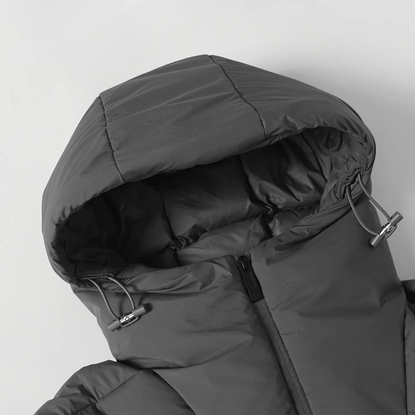The design of the P860 Moncler Fusain short down jacket is inspired by the thrilling racing sports, echoing the three-dimensional tailoring and dynamic structure of the racing driver's uniform. Diamond quilting is used to build a thermal barrier, and the lightweight fabric is full of fluffy warmth. The silhouette is neat and not bulky, and the hooded design adds casualness. It is made of quilted nylon fabric, which has excellent warmth and protection. It is not only a textured armor to resist the cold wind when commuting, but also a fashion tool to create a minimalist and high-end feel when going out. In the cold winter, you can achieve the dual elegance of temperature and style with a piece of down. The short design features reflective zippers for a modern look. Code number: 12345 Color: black, gray