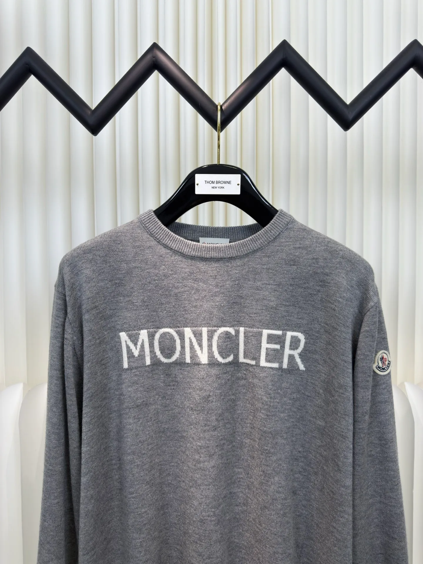 P440 MONCLER jacquard crew neck sweater is made of wool blended fabric, mainly 95% wool, combined with 4% nylon and 1% spandex. The main body of wool ensures the warmth and comfort of the clothing. The addition of a small amount of nylon and spandex significantly improves the elasticity and wear resistance. The ribbed decorative parts are made of 100% wool, which further enhances the overall texture.  Through the high needle count and fine gauge loom, combined with the orderly direction of the internal yarn, the floating threads are cleverly woven and stored, with almost no unnecessary thread mess. The color switching of each group of letters is synchronized with the knitting needles in milliseconds, forming a delicate letter LOGO jacquard decoration on the chest. Size S M L XL