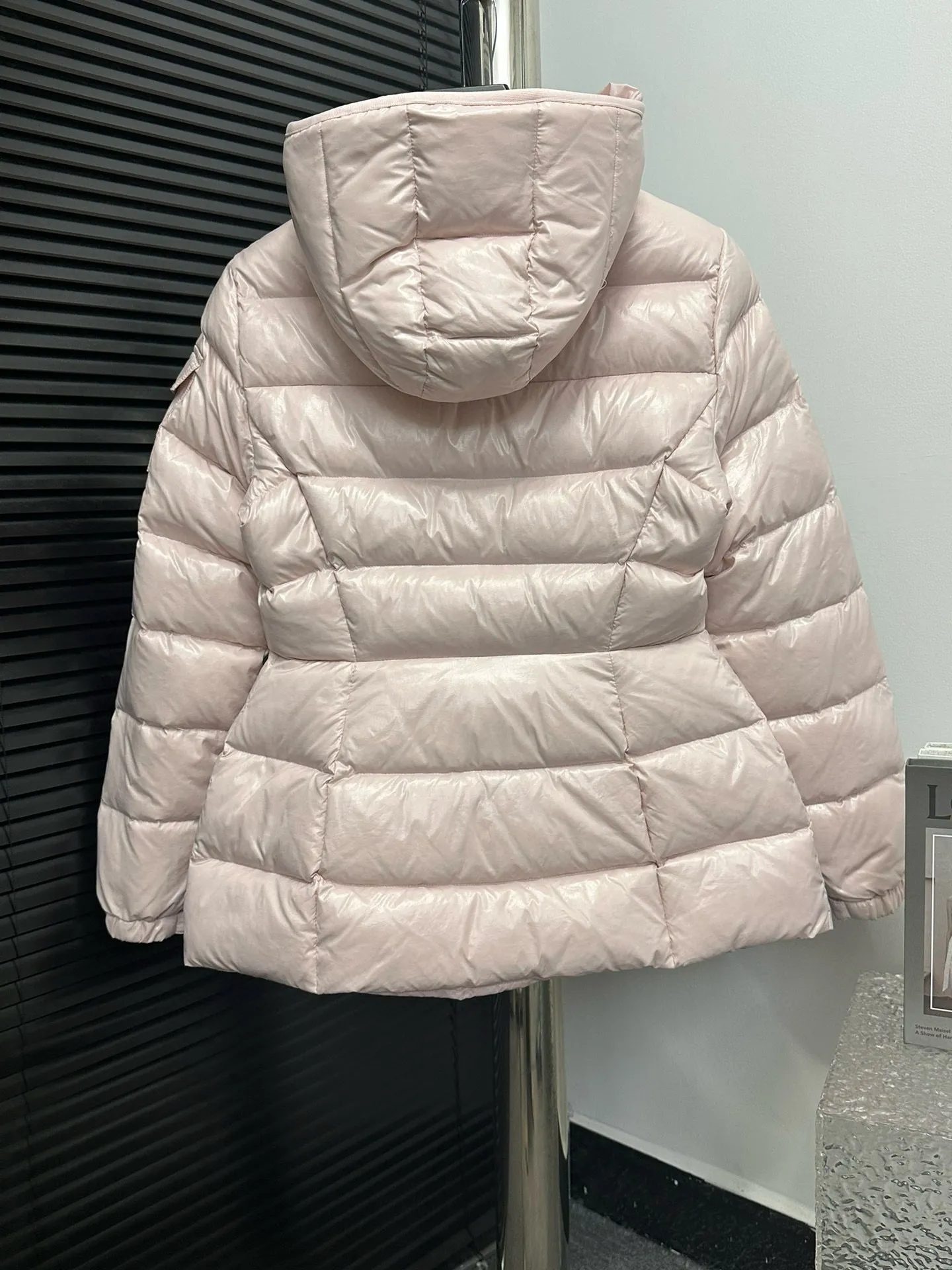 P860 [Moncler] Hooded, waisted women's short down jacket. The barante down jacket is made of glossy nylon fabric and is inspired by the 1970s. It adopts a waist design and presents an A-line silhouette, highlighting a feminine style. An adjustable hood and signature logo patch add finishing touches. Details · Made of lon laqué fabric · lon laqué lining · Filled with down · Adjustable hood · Zipper and snap closure · Suit pocket · Adjustable cuffs Size: 0/1/2/3