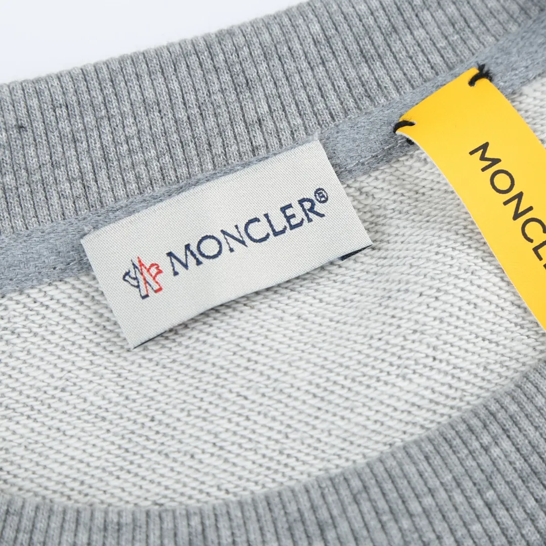 P370 MONCLER printed round neck sweatshirt Fabric selection: Single-sided fish scale fabric woven with cotton as the base. The front is a smooth knitted surface, and the skin-touching surface is formed into three-dimensional terry through the floating thread knitting technology of the knitting machine, which increases the fluffiness and has a delicate touch. The terry structure absorbs a large amount of water and evaporates quickly, so it is not easy to loosen and deform after repeated washing.  Process 1: Use glue printing to present 4 high-saturation patterns on the fabric. The pressure of the scraper is even, and the scraping printing is done in 3 times to ensure that the glue is fully penetrated and covered. After curing at high temperature, the pigment is firmly bonded to the cotton fiber. The ink-absorbing and penetrating properties of the cotton fiber make the pattern less likely to fall off due to friction.  Process 2: The 2*2 rib formed by alternating longitudinal rows of front coils and longitudinal rows of back coils is still very elastic and has a wide pattern that fits the wrist and waist without a sense of restraint. The gaps between the coils allow air to circulate without losing warmth.  Process 2: By actively interfering with the shrinkage potential of cotton fibers, the fabric is able to transition from changeable to stable, improving dimensional stability while being less prone to deformation and wrinkles.  Accessories: One to one customized 3-standard SIZE: S M L XL