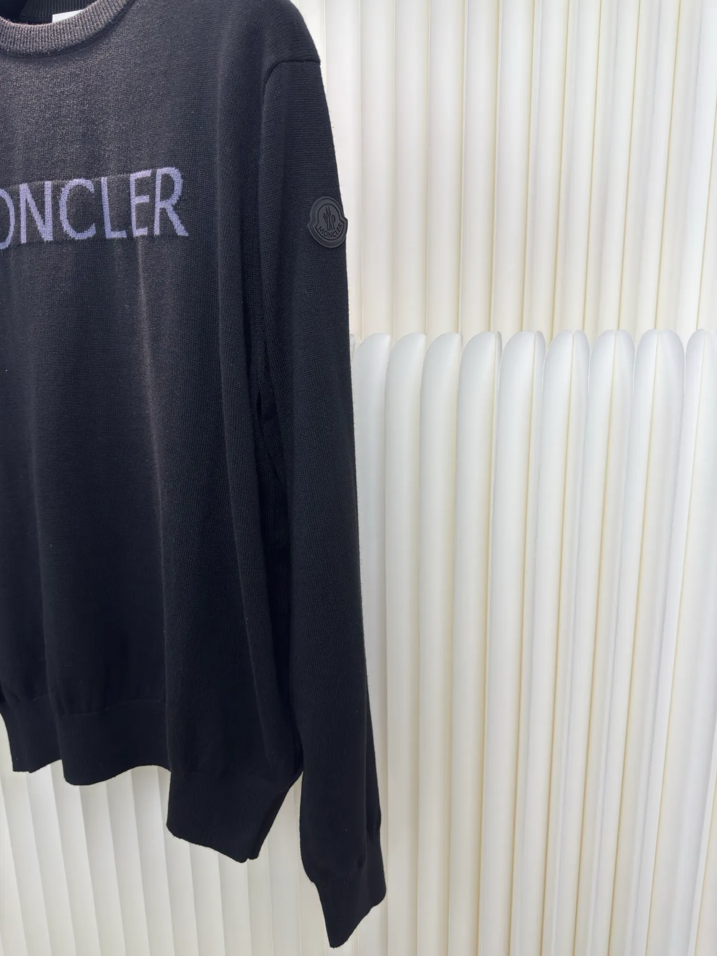 P440 MONCLER jacquard crew neck sweater is made of wool blended fabric, mainly 95% wool, combined with 4% nylon and 1% spandex. The main body of wool ensures the warmth and comfort of the clothing. The addition of a small amount of nylon and spandex significantly improves the elasticity and wear resistance. The ribbed decorative parts are made of 100% wool, which further enhances the overall texture.  Through the high needle count and fine gauge loom, combined with the orderly direction of the internal yarn, the floating threads are cleverly woven and stored, with almost no unnecessary thread mess. The color switching of each group of letters is synchronized with the knitting needles in milliseconds, forming a delicate letter LOGO jacquard decoration on the chest. Size S M L XL