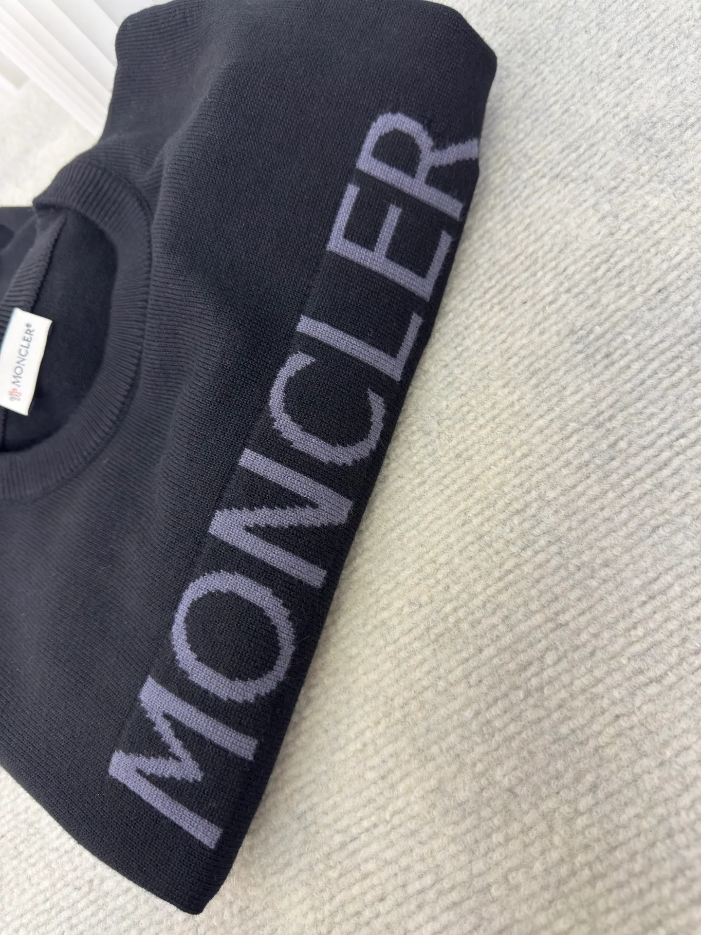 P440 MONCLER jacquard crew neck sweater is made of wool blended fabric, mainly 95% wool, combined with 4% nylon and 1% spandex. The main body of wool ensures the warmth and comfort of the clothing. The addition of a small amount of nylon and spandex significantly improves the elasticity and wear resistance. The ribbed decorative parts are made of 100% wool, which further enhances the overall texture.  Through the high needle count and fine gauge loom, combined with the orderly direction of the internal yarn, the floating threads are cleverly woven and stored, with almost no unnecessary thread mess. The color switching of each group of letters is synchronized with the knitting needles in milliseconds, forming a delicate letter LOGO jacquard decoration on the chest. Size S M L XL