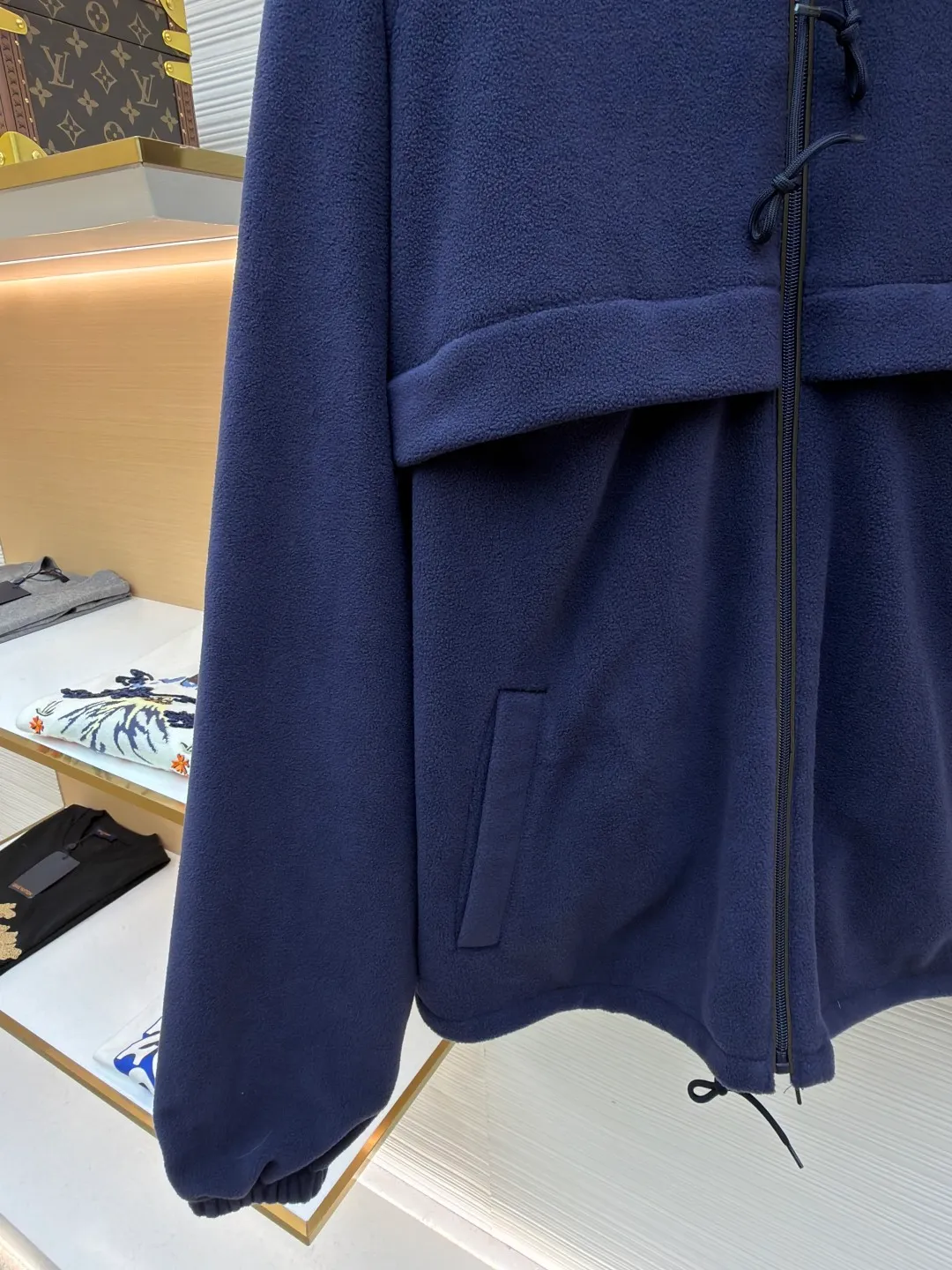 Prada hooded drawstring fabric short jacket ●Original version: Purchased and developed for 22300 ●Item number: 1682436-B25 ●Fabric: polar fleece fabric ●Technology: hand-sewn label production ●Color: navy blue ●Version: fitted version ●Weight: about 720 grams ●Size: 46-48-50-52 ●Description: This PRADA hooded drawstring fabric short jacket is made of high-quality fabric as the core material. It is first treated with an enzyme washing process to make the fabric soft and skin-friendly. It also enhances the wrinkle resistance and color fastness of the fabric, making the navy blue tone more textured and not easy to fade. The body is designed with a short cut and is equipped with a hooded drawstring structure. The drawstring is treated with reinforced stitching to ensure smooth adjustment and durability. The shoulders are made of raglan sleeves, which improves the freedom of movement of the wearer. Flat seams are used at the splicing between the pockets and the body, and the stitching is neat and precise. The brand logo is fixed through hand-sewing technology, and the stitching is even and firm, retaining the brand texture. The entire garment is stitched with high-tenacity stitches of the same color. The measurement error of 1~3cm is within the normal range. The overall craftsmanship takes into account both functionality and luxury details. Hand washing is recommended to maintain the integrity of the fabric and craftsmanship. The overall wiring is straight and delicate, the fabric is comfortable and soft, and the color is consistent without color difference. It can be matched with the same style to create a fashionable look and control various occasions. Customized accessories, complete with three standards, same style for men and women!