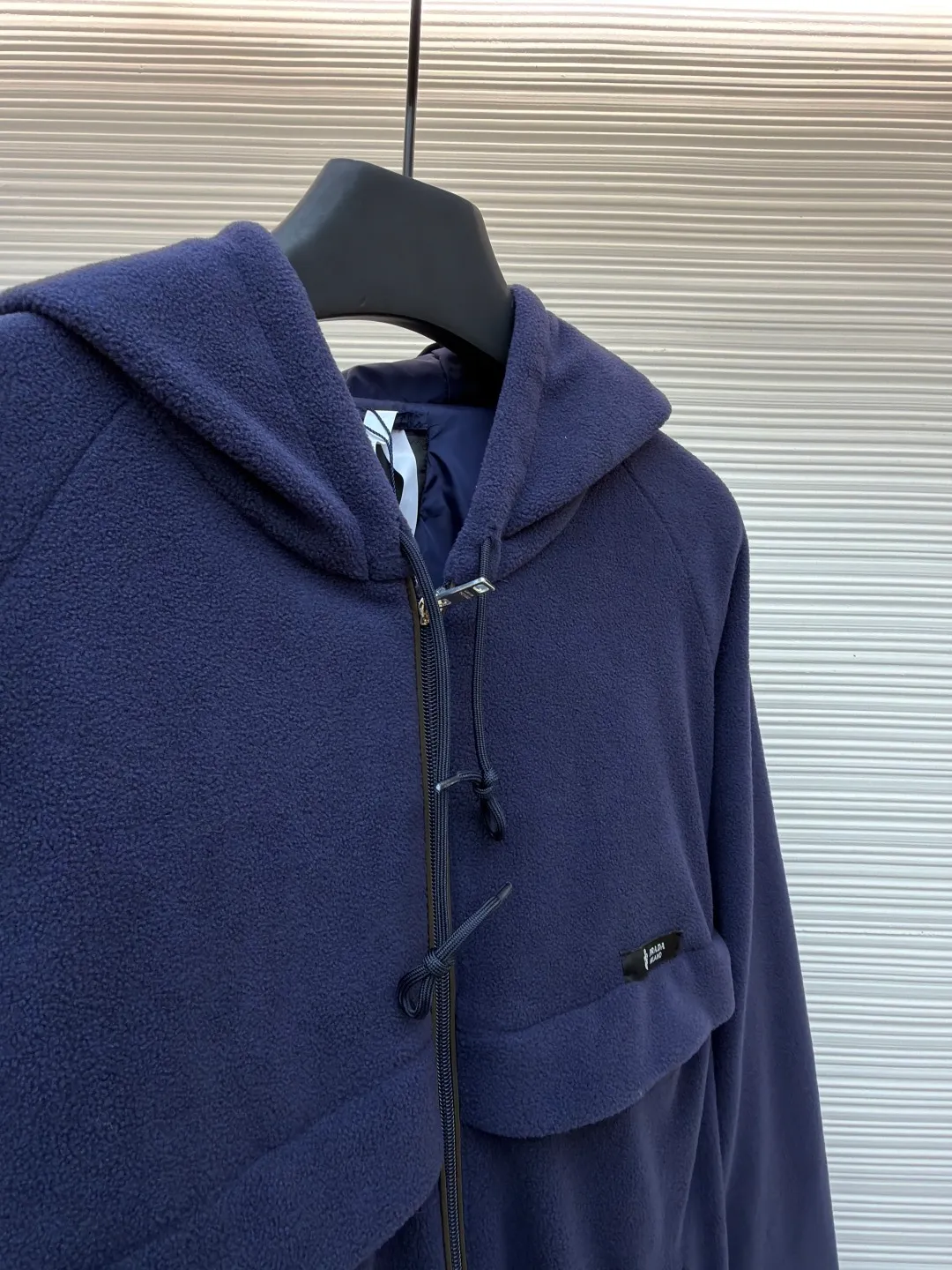 Prada hooded drawstring fabric short jacket ●Original version: Purchased and developed for 22300 ●Item number: 1682436-B25 ●Fabric: polar fleece fabric ●Technology: hand-sewn label production ●Color: navy blue ●Version: fitted version ●Weight: about 720 grams ●Size: 46-48-50-52 ●Description: This PRADA hooded drawstring fabric short jacket is made of high-quality fabric as the core material. It is first treated with an enzyme washing process to make the fabric soft and skin-friendly. It also enhances the wrinkle resistance and color fastness of the fabric, making the navy blue tone more textured and not easy to fade. The body is designed with a short cut and is equipped with a hooded drawstring structure. The drawstring is treated with reinforced stitching to ensure smooth adjustment and durability. The shoulders are made of raglan sleeves, which improves the freedom of movement of the wearer. Flat seams are used at the splicing between the pockets and the body, and the stitching is neat and precise. The brand logo is fixed through hand-sewing technology, and the stitching is even and firm, retaining the brand texture. The entire garment is stitched with high-tenacity stitches of the same color. The measurement error of 1~3cm is within the normal range. The overall craftsmanship takes into account both functionality and luxury details. Hand washing is recommended to maintain the integrity of the fabric and craftsmanship. The overall wiring is straight and delicate, the fabric is comfortable and soft, and the color is consistent without color difference. It can be matched with the same style to create a fashionable look and control various occasions. Customized accessories, complete with three standards, same style for men and women!