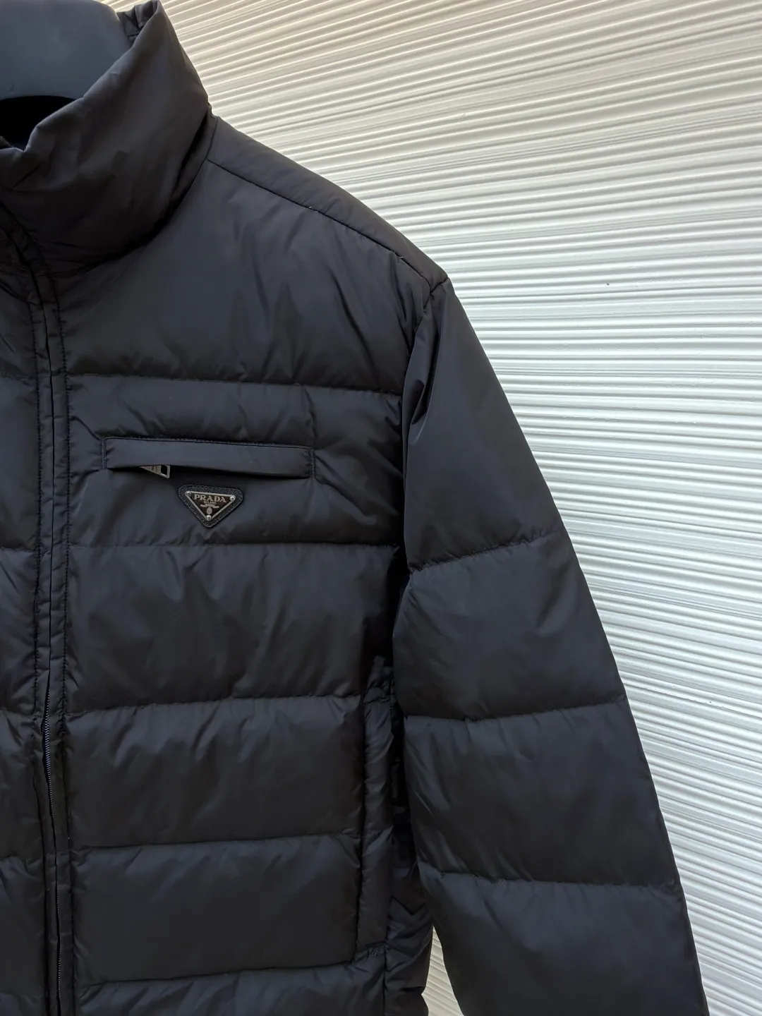 Prada triangle pocket down jacket ●Original version: Purchased and developed in 19800 ●Item number: 1681902-D20 ●Fabric: white duck down fabric ●Technology: mechanical down filling ●Color: black ●Version: fitted version ●Weight: about 675 grams ●Size: 46-48-50-52 ●Description: Customized ultra-dense round hole woven fabric (with anti-repellent treatment) showing a matte micro-texture Use the new national standard 90 white duck down (welcome to test), full of down, full of warmth, you are in a warm cloud, surrounded by soft warmth, the classic black tone exudes an innate sense of luxury, the iconic enameled metal triangle logo is embellished on the chest, low-key and powerful, the stand-up collar is crisp and stylish, accurately fits the neck curve, and uses architectural lines to reconstruct the warmth and neatness of the bloated down jacket. Enjoy warmth and comfort. Become the most considerate companion for mechanical down filling in winter. Prioritize the filling area by making the liner pattern to determine the gram weight of down per square meter according to the original three-dimensional effect, thereby calculating the filling amount of each piece. The computer down filling machine uses a digital weighing unit to achieve stable measurement, and uses imported special machine infrared to locate the "Prada triangle mark" for more accurate positioning. The firm and strong template machine opens the zipper bag. The lines are smooth and tidy. The wiring is even and the template machine lines the lines. The line process of the computer template machine shows extremely high neatness and smoothness. The craftsman accurately controls the size during the operation to ensure that each line meets the design requirements. The lines of the entire template are smooth and uniform, clean and beautiful. The overall wiring is straight and delicate, the fabric is comfortable and soft, and the color is consistent without color difference. It can be matched with the same style to create a fashionable look and control various occasions. Customized accessories, complete with three standards, same style for men and women!