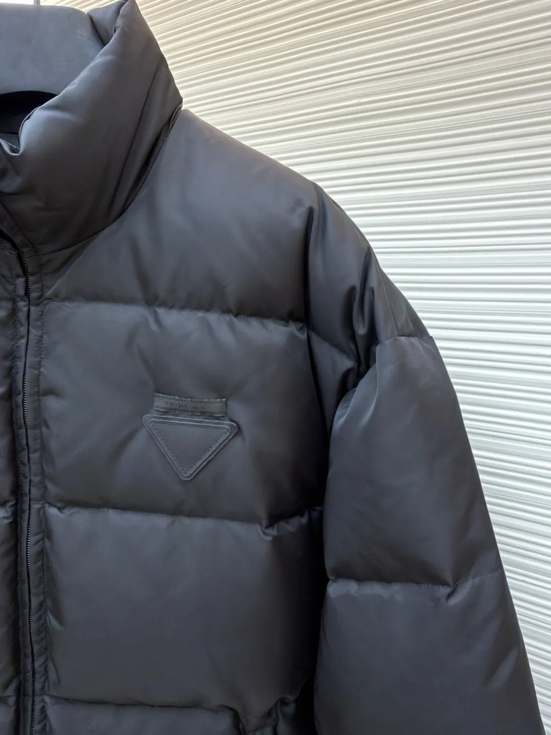 Prada nylon triangle down jacket ●Original version: Purchased and developed by 13557 ●Item number: 1681282-C95 ●Fabric: white duck down fabric ●Technology: mechanical down filling ●Color: black ●Version: fitted version ●Weight: about 1025 grams ●Size: S-M-L-XL ●Description: Made of high-count and high-density nylon woven fabric, it is a lightweight, strong and fine-textured advanced fabric. Its physical complexity lies in the fact that while achieving extreme lightweight, it provides excellent tear resistance and abrasion resistance through a dense fabric structure, solving the industry problem of light weight and durability that are often contradictory. Waterproof coating: This is not a simple film, but a microscopic functional polymer layer coated on the surface of the fabric after it is woven. Its complexity is reflected in its chemical properties: it can effectively reduce the surface tension of the fabric, making it impossible for water droplets to penetrate its fiber gaps, thereby forming a lotus leaf effect and achieving efficient waterproofing. At the same time, this coating usually has a certain degree of breathability, allowing moisture emitted by the body to escape and maintaining a comfortable internal microclimate. This is a precise balancing technology. The laser-burned triangle mark on the chest is the pinnacle of the complexity of the entire garment's craftsmanship. Laser burning is a non-contact precision processing technology. Using a laser beam of specific wavelength and energy, the fibers on the surface of the fabric are vaporized according to a preset digital path. The laser can accurately "carve" every detail of the logo without damaging the underlying fabric structure, with clear and sharp edges and a unique, slightly burning matte texture. This is completely different from traditional embroidery or offset printing. It is integrated with the fabric itself and cannot be peeled off. It also requires extremely high stability in process control - if the energy is slightly weaker, the pattern will be unclear, and if the energy is slightly stronger, it may penetrate the fabric. The core is filled with 90% pure white duck down. "90% pure white duck down" is an indicator that has been strictly sorted. The thermal insulation principle of down is that its three-dimensional velvet can hold a large amount of still air and form an efficient thermal insulation layer. To sum up, every part of this down jacket goes beyond basic functions and embodies full-link innovation and quality control from raw material selection, textile engineering, chemical processing to digital finishing. The overall wiring is straight and delicate, the fabric is comfortable and soft, and the color is consistent without color difference. It can be matched with the same style to create a fashionable look and control various occasions. Customized accessories, complete with three standards, same style for men and women!