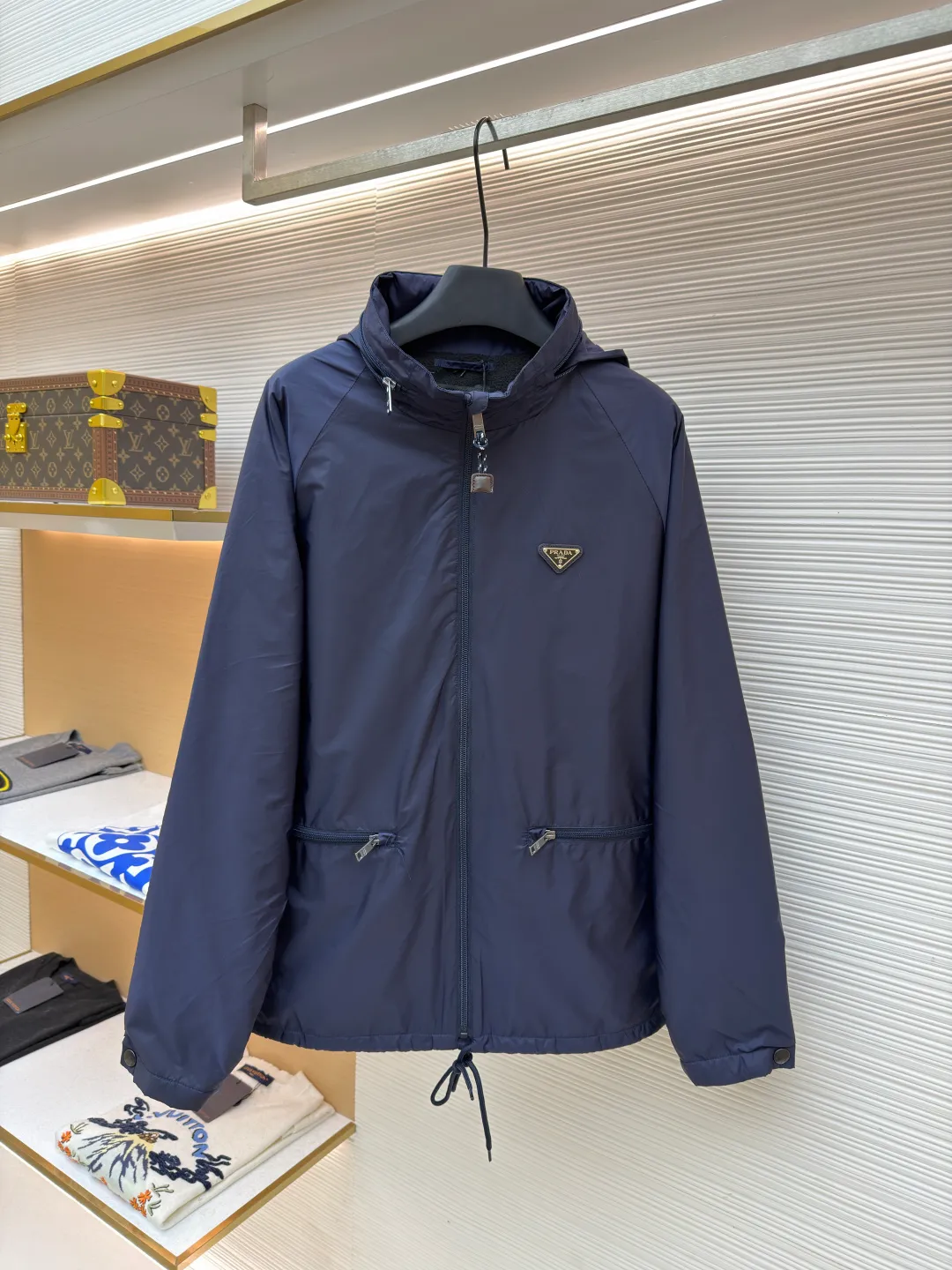 Prada Regenerated Nylon Fleece Jacket ●Original version: Purchased and developed by 12048 ●Item number: 1682331-B70 ●Fabric: Regenerated nylon fabric ●Technology: Made on positioning cutting machine ●Color: Navy blue ●Version: Fitted version ●Weight: about 585 grams ●Size: S-M-L-XL ●Description: High-density yarn is made by melt spinning through a special process. The yarn has been stretched and twisted through multiple processes to give the fabric the stiffness and wrinkle resistance that are comparable to those of native materials, while retaining a light and drapey wearing experience. The surface of the fabric is treated with an environmentally friendly coating process to form a micro-waterproof film layer, which is both windproof and breathable. The main raw material is polyester fiber blended wool raw material which is cleaned and pre-treated to remove impurities. After the yarn is woven into fabric through a loom, it is brushed, that is, the surface of the fiber is fluffed through mechanical brushing to form fluff. Then the shaking process is carried out, and the fabric is shaken under high temperature and humid conditions, so that the fibers form small spherical particles to increase the thermal insulation performance. The shoulder splicing uses twill sewing technology, the raglan sleeve design releases shoulder movement space, and the regular shoulder line ensures the stiffness of the overall silhouette, maintaining an elegant silhouette for both sports and static wear. The three-dimensional pleat design is incorporated into both sides of the body and sleeve elbows, and a long-lasting pleat texture is formed through high-temperature setting technology. This not only enhances the aerodynamic performance of the fabric, but also enriches the visual hierarchy with light and shadow changes, breaking the dull feeling of solid color fabrics. The cuffs are equipped with a hidden snap-button adjustment system, which can be freely tightened according to the circumference of the wrist to prevent cold wind from entering; the straight bottom edge is matched with a drawstring at the hem, and the inner rope buckle design can be used to adjust the tightness, taking into account warmth preservation and waistline shaping. The overall wiring is straight and delicate, the fabric is comfortable and soft, and the color is consistent without color difference. It can be matched with the same style to create a fashionable look and control various occasions. Customized accessories, complete with three standards, same style for men and women!