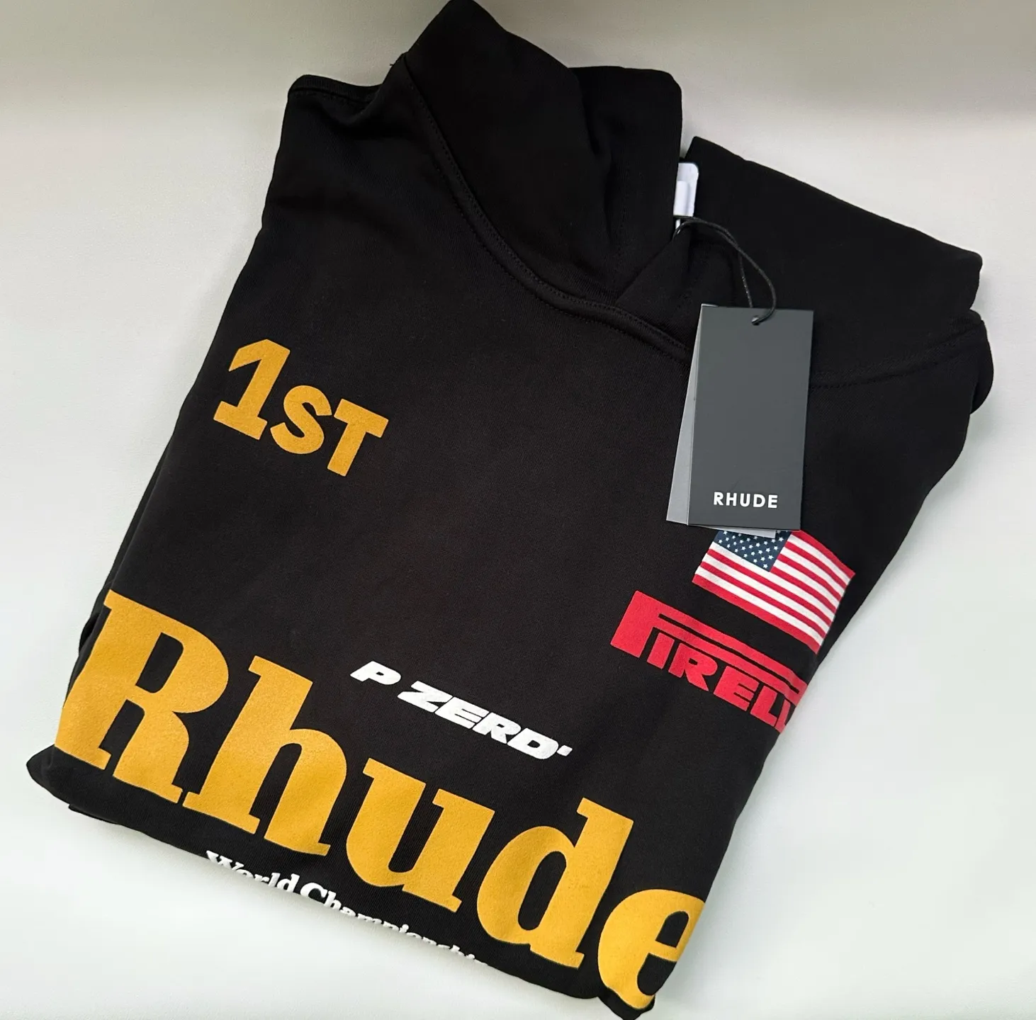 Style number: 8888 P246 RHUDE × PIRELLI Burning Aesthetics New Hooded Sweatshirt When the speed language of racing enters the fashion context, the cooperation between RHUDE and PIRELLI has become a precise and restrained cultural injection. 	 Suede printing process + using pure cotton terry brushed process fabric 450 grams, heavy upper body three-dimensional fluffy Size: (S-M-L-XL) Color: black