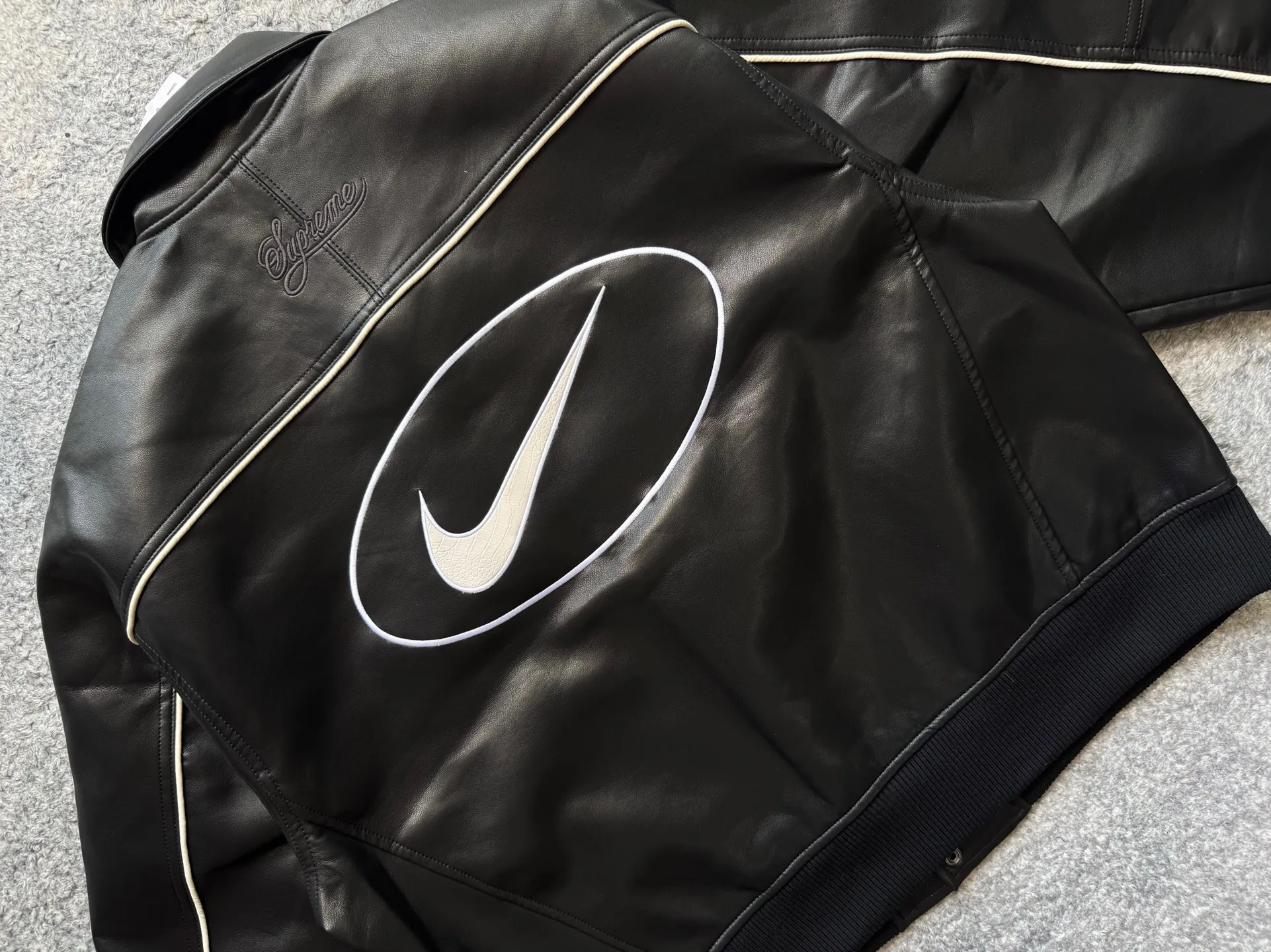 P540 [First release on the whole network, top version] Supreme xNike joint model SS25 WEEK4 Leather Varsity Jacket Back logo leather varsity jacket, same style for men and women. The fabric is made of original 1:1 fabric, and the original customized lining is made of ‌Var Satin‌ fabric: it has enough elasticity and drape, strong gloss, and is not easy to wrinkle. Breathability is good. Color: Black, White Size: S-XL Length Bust Sleeve Length S 64 128 72 M 66 132 74 L 68 136 76.5 XL 70 140 79