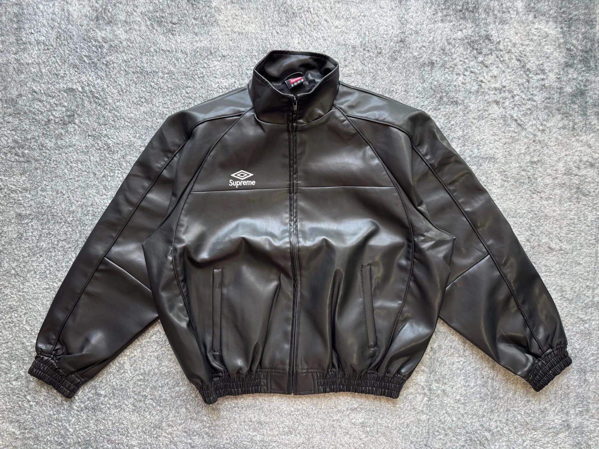 P590 Supreme Umbro joint model FW25 WEEK4 Leather Track Jacket embroidered logo zipper closure leather jacket, same style for men and women, made of lambskin material, mesh lining. Welted zippered hand pockets at lower front and internal chest pocket. Elasticized cuffs and hem in leather. Embroidered logo at chest and back neck. Color: Black, Navy, Pink Size: S M L